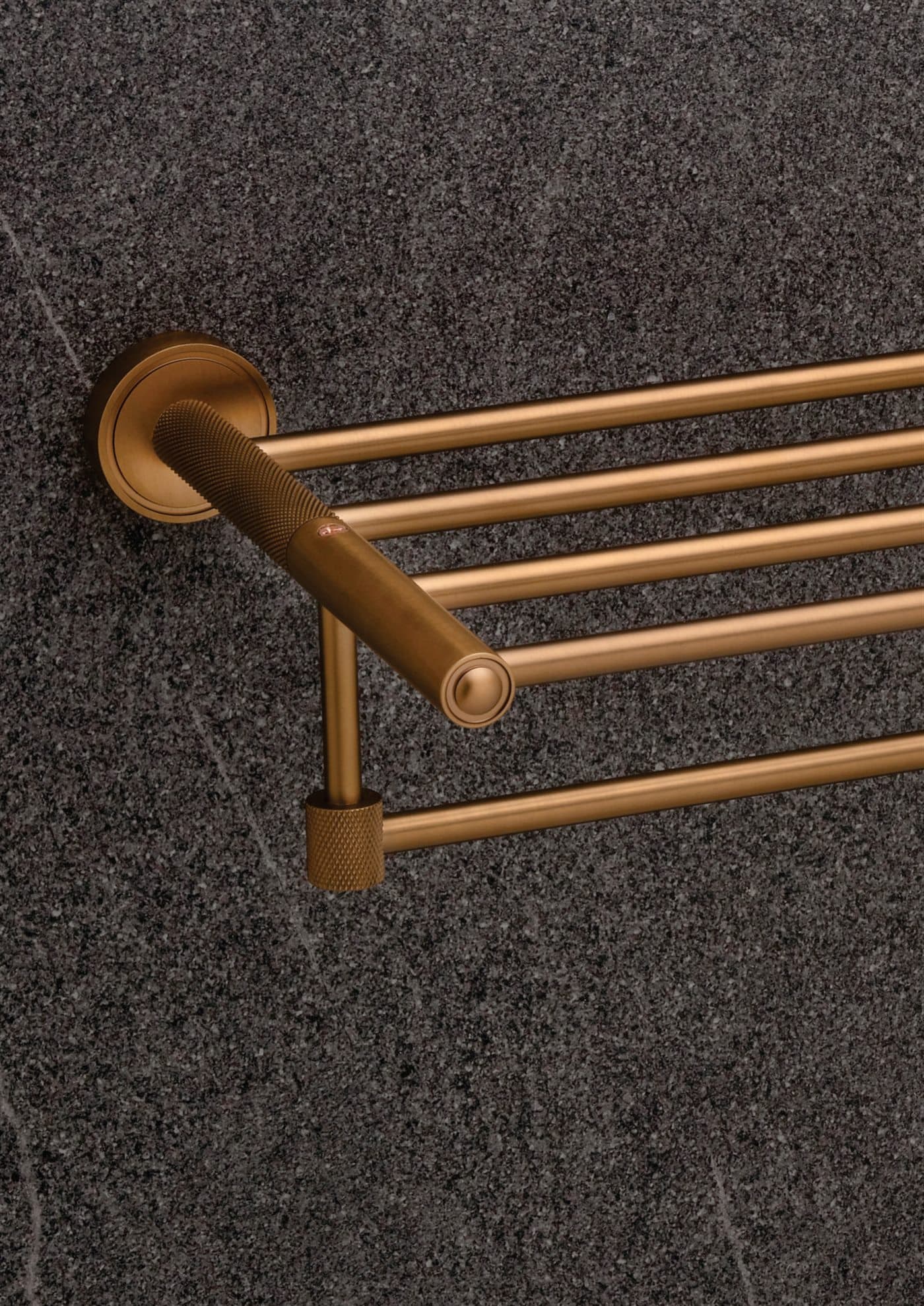 Brushed-bronze towel rack on dark granite